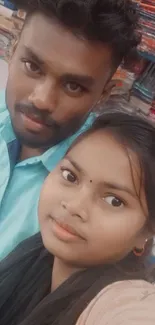 Casual selfie of a young couple with vibrant background.