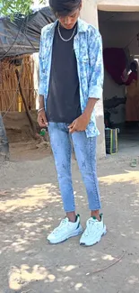 Man in denim standing outside rustic house.