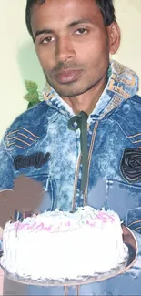 Person in denim jacket holding a cake, creating a casual portrait wallpaper.