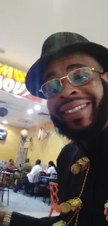 Smiling man in hat at a lively restaurant.