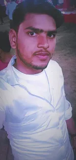 Casual portrait of a young man at an evening event, wearing a white shirt.