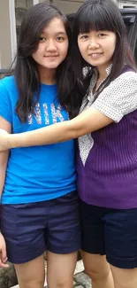 Two women embracing in casual, colorful attire.