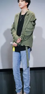 Person in green jacket with microphone and blue jeans.