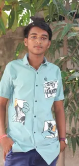 Young man in green shirt against leafy backdrop.