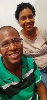 Smiling couple in casual attire sitting indoors.