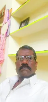 Casual home portrait with beige background and shelves.