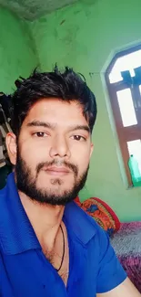 A relaxed young man sitting indoors in natural light.