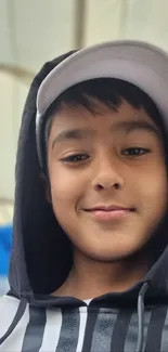 Young boy wearing a hoodie with a cap.