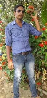 Casual youthful person in denim against lush green backdrop with red flowers.