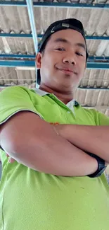 Confident person in green shirt standing indoors.