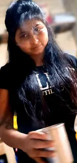 Young woman in black t-shirt holding a cup at home.