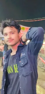 Young man at a bustling market with vibrant lights.