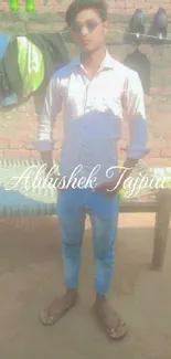 Young man posing against a brick wall with stylish casual attire.