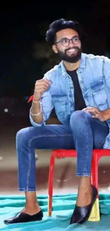 Man in casual denim outfit sitting outdoors.