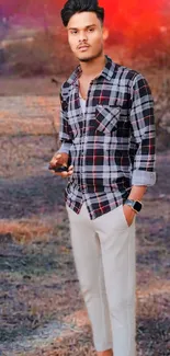 Man in plaid shirt with white pants outdoors.