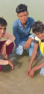 Three young men pose casually in a lake setting.