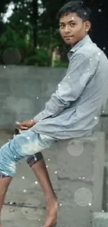 Young person sitting outdoors with nature backdrop.