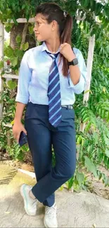 Woman in blue office attire surrounded by greenery.