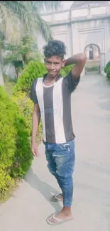 Young man posing on a garden pathway with greenery.