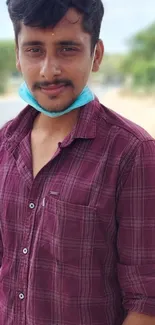 Casual portrait of man in maroon plaid shirt outdoors.