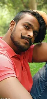 Man in pink shirt relaxing in a lush green garden.