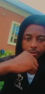 Young man outdoors in a hoodie, relaxed portrait style.