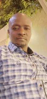 Casual portrait of a man in a plaid shirt outdoors.