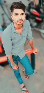 Casual young man sitting outdoors in jeans and shirt.