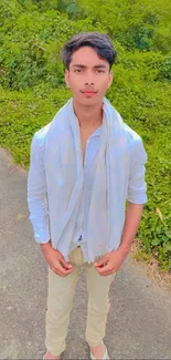 Young man posing outdoors in casual attire, light blue theme.