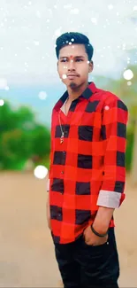 Outdoor portrait of a man in a red checkered shirt with a nature background.