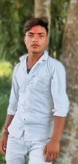 Young man in white shirt with green nature backdrop.