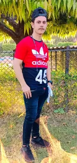 Young man in red shirt outdoors with green background.