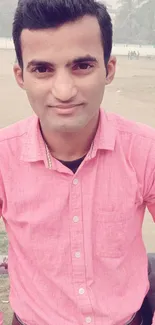 Man in pink shirt outdoors with a casual look.