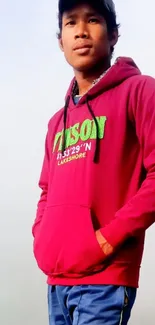 Young man in magenta hoodie with foggy background.