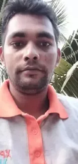 Casual portrait of a man outdoors with palm leaves.