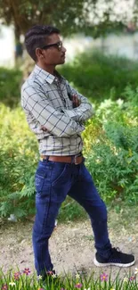 Man posing in a natural green outdoor setting with floral foreground.