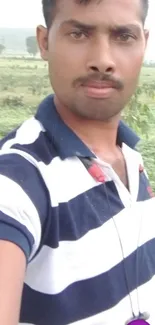 Casual selfie in striped shirt with nature background.