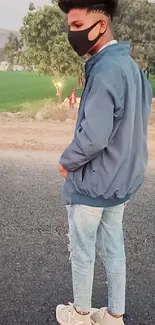 Person in casual attire, standing on street with nature background.