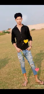 Young man in casual clothes standing outdoors in green field.