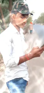 Young man in a cap using phone outdoors.