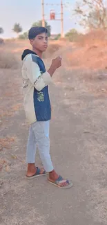 Young person standing on a dirt path in a rustic outdoor setting.