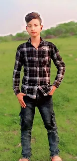 Young person in a plaid shirt standing in a vibrant green field, mobile wallpaper.