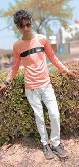 Man in casual attire posing in park setting.