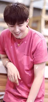 Mobile wallpaper of a young man in a pink shirt with a casual smile.