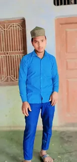 Man in blue outfit standing indoors with vibrant background.