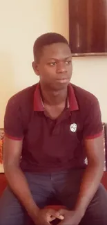 Young man sitting indoors casually, relaxed atmosphere.