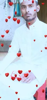 A young man in white traditional attire seated indoors.