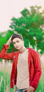 Young man in red shirt posing in a green field.