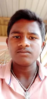 Young man in pink shirt, warm light portrait.