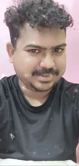 Person in black shirt with pink wall background.